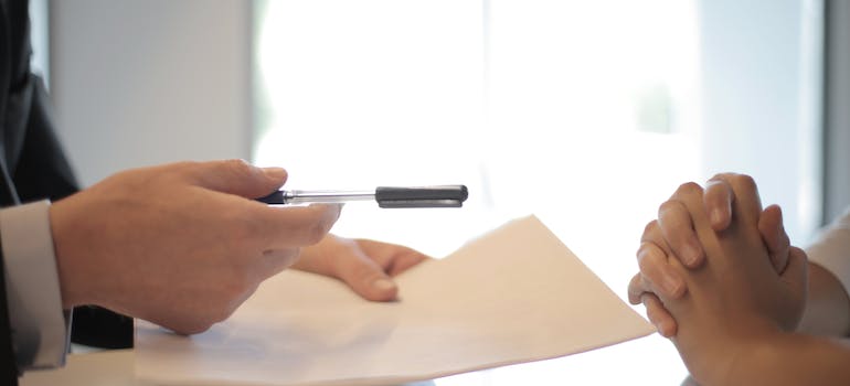 A person handing someone a document to sign