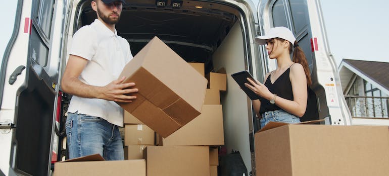 Movers packing boxes into a van and discussing a guide for Manhattan moves