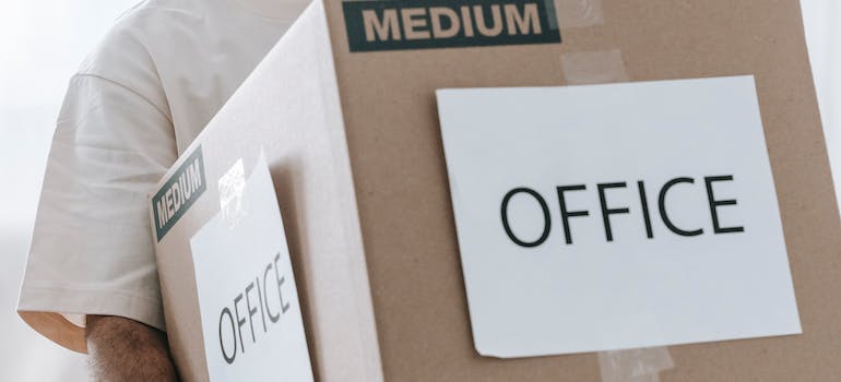 A person carrying a labeled box to store during a divorce