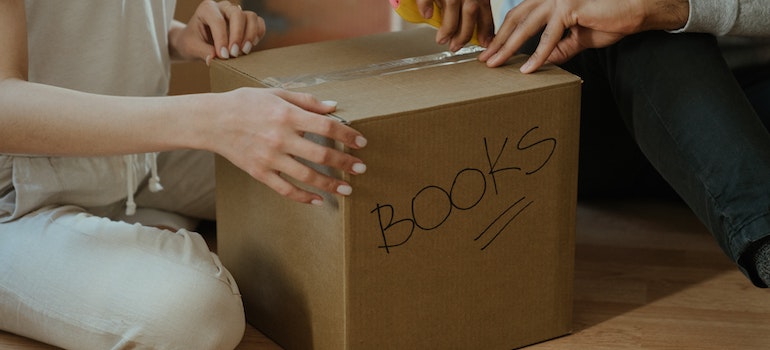 Two people packing a cardboard box for short-term storage in Manhattan