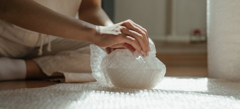 A woman using bubble wrap to pack something for a move
