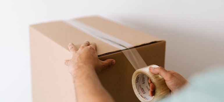 A person putting tape on a box