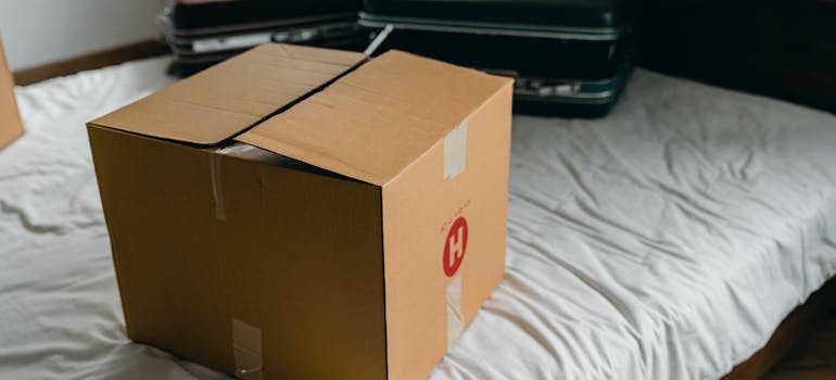 A moving box and suitcases on a bed