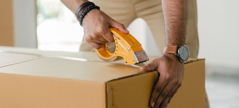 A man taping up a moving box when packing for his pet-friendly move