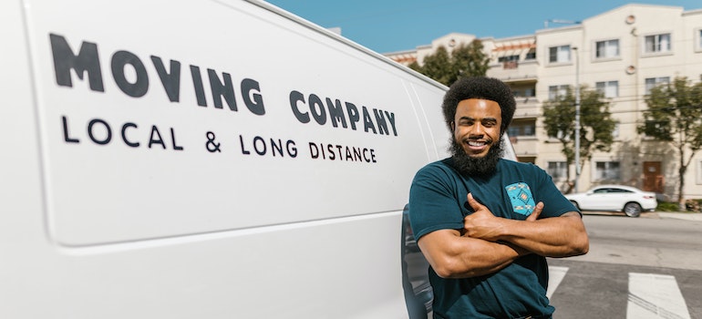 A mover standing beside a moving company van