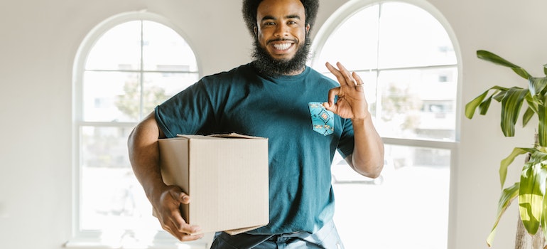 A man in green holding a cardboard box