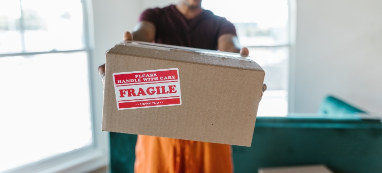 A man holding a moving box with a fragile sticker on it