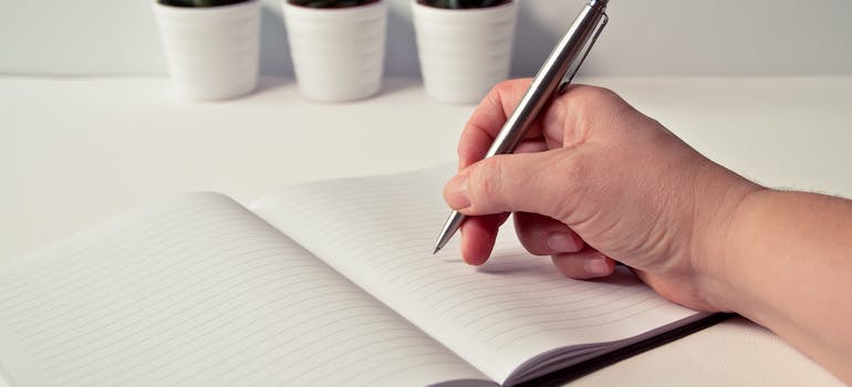 A person writing down a detailed timeline of the strategies for successful commercial relocations they want to use