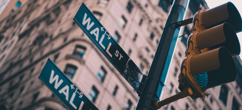 A traffic light and signs that point to wall street
